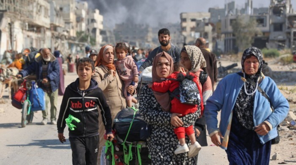 Palestinians displaced from shelters in Beit Hanoun cross the main Salaheddine road into Jabalia in the northern Gaza Strip