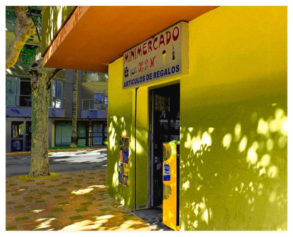 Colour adjusted photograph showing a sun dappled Spanish mini market on a street corner.