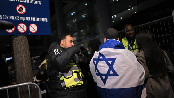 Israelische Fans kommen zum Spiel Frankreich gegen Israel und unterhalten sich mit der Polizei. Ein Fan hat eine Israel-Flagge um den Körper. 