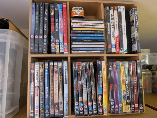 Photo of a collection of DVD's and CD's. A small toy Volkswagen Type 2 camper also.