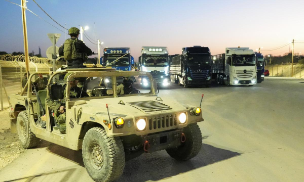 Soldados israelíes vigilan camiones que transportan ayuda humanitaria en el paso fronterizo de Erez, al norte de Gaza, el 21 de octubre de 2024. (Janis Laizans / Reuters)