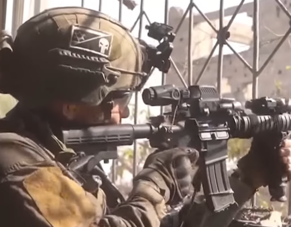 A photo of an IOF soldier, facing to shoot out of a cast iron grated window. He's wearing typical battle gear, holding an M4 derivative, and wearing a helmet with a black and white patch on it. the patch is a stylised black and white Israeli flag, sliced diagonally to reveal and punisher symbol