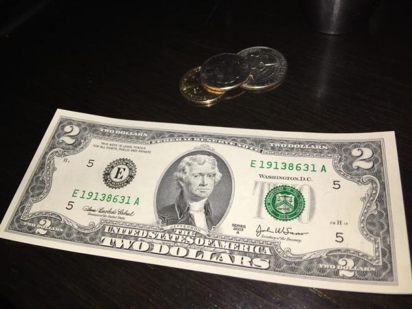 American $2 note and a few coins on a table.