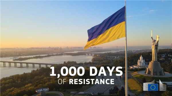 The image shows the Ukrainian flag prominently waving over a cityscape, featuring the iconic Motherland Monument in Kyiv during sunrise. Below the flag, the text reads, "1,000 DAYS OF RESISTANCE," accompanied by the European Commission logo.