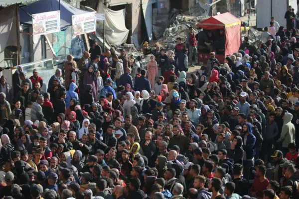 Palestinians wait for fresh bread outside a bakery in the southern Gaza city of Khan Younis on Wednesday [Eyad Baba/AFP]