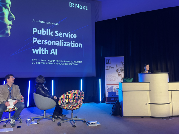 A stage, speakers, a slide saying “public service personalization with AI”