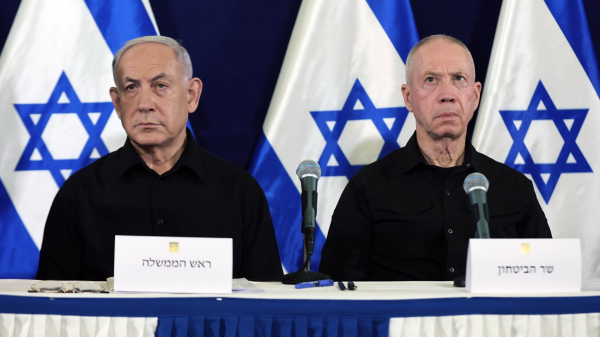 Benjamin Netanyahu and Yoav Gallant on a picture side by side, wearing matching black shirts, having white nameplates in front of them that basically beg to be photoshopped to mugshots