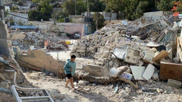 Un nen camina davant d'una casa enderrocada al barri d'Al Bustan (3Cat/J. Brescó)