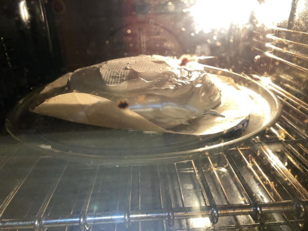 A rounded white heaping of pavlova on a round baking tray in the oven.