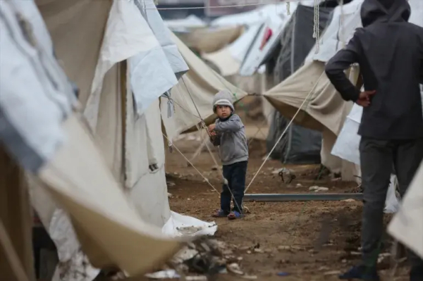 A child adjusts a tent rope in the camp inside the former stadium [Dawoud Abo Alkas/Anadolu]