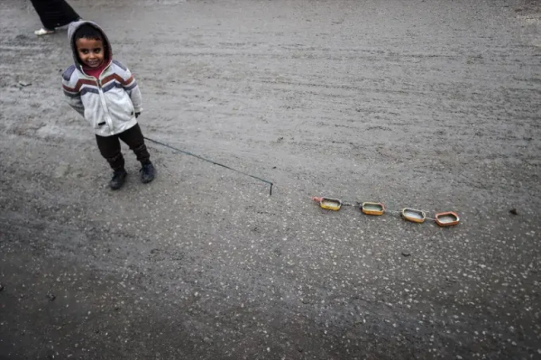 A child plays with a toy made of food tins in a makeshift camp in Deir el-Balah, Gaza on Sunday [Ali Jadallah/Anadolu]