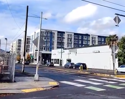 looking left, a breakaway sign post with flashing lights, smack in the middle of a sidewalk while the street has way more clear width than necessary for 20mph speeds