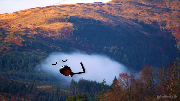 A photo of a partially wooded mountain. Nestled near the bottom, behind some evergreen trees, is a low single cloud. Above it the hillside becomes treeless, lit by a low autumn sun. There is a hint of grey sky above. The cloud has a yawning face drawn on, arm reaching up to cover their month, eyes still closed.