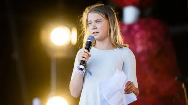 Photo of Greta Thunberg, holding a microphone and speaking at a recent event.