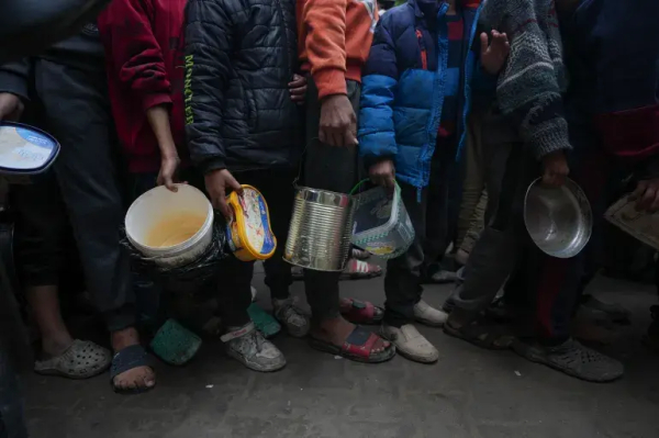 Palestinian children queue at a food distribution kitchen in Deir el-Balah, central Gaza [Abdel Kareem Hana/AP]