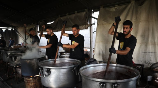 Vrijwilligers in een van de gaarkeukens van WCK in Gaza eerder dit jaar. Ze staan in een tent en roeren met een lange spaan in grote pannen