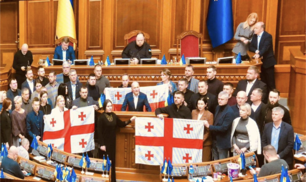 Ukrainian MPs stand in parliament with Georgia flags.