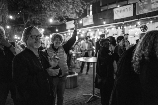 In a black and white photo, people celebrate the Texas Observer's 70ths annviersary in a courtyard. 