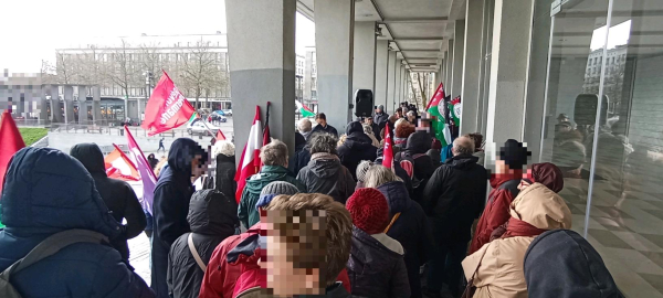 Rassemblement sous le préau de l'hôtel de ville.
Une personne fait un discours.
Des drapeaux palestiniens sont dressés. 