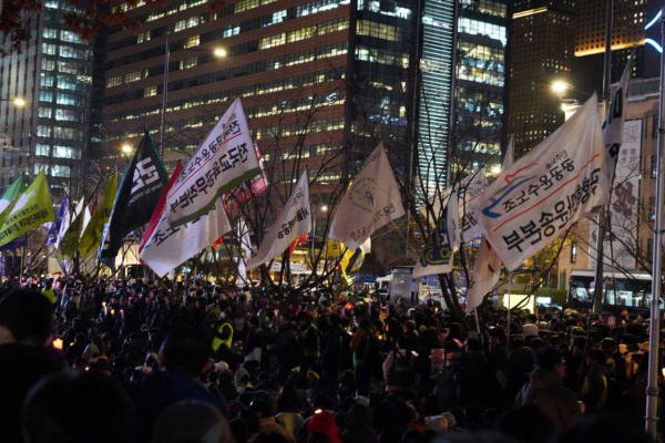 A large crowd in the streets waving flags in Korean