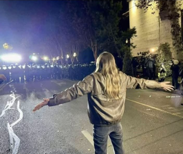 In Tbilisi Georgia, a lone woman protestor stands with her arms outstretched in a confrontation with a row of about 50 riot police with shields.