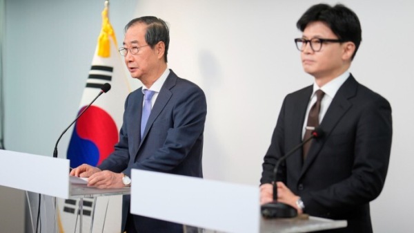 South Korean Prime Minister Han Duck-soo speaks at a podium as Han Dong-hun of the ruling People Power Party listens from a podium next to him during their joint statements in Seoul