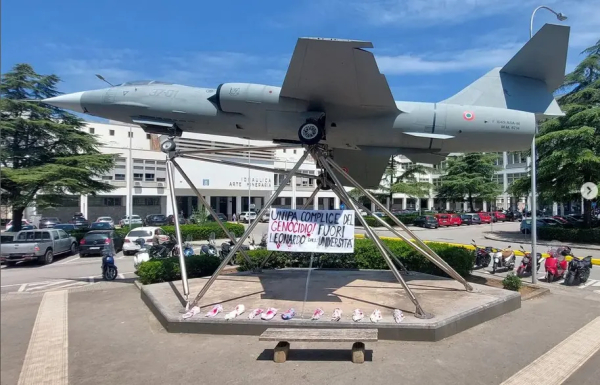 In Italy outside Leonard plant Palestine solidarity protesters have left children’s shoes and a sign pointing out Leonardo and Genocide under a display war plane 