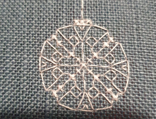 Serious close up of a white bauble, lots of lines at different angles and a few crosses done diagonally to make up a round detailed bauble. 