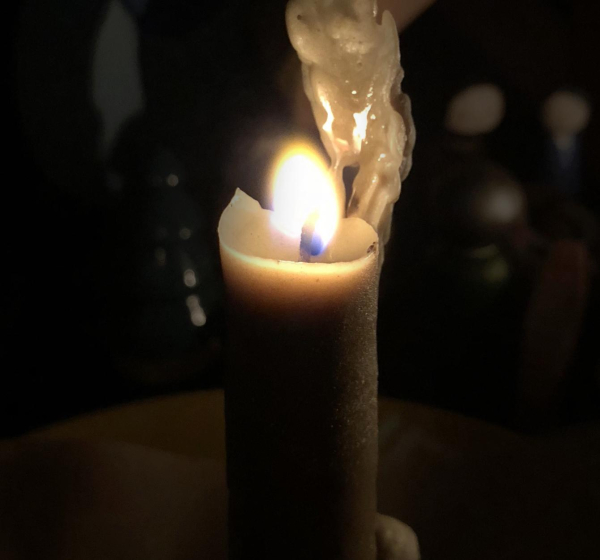 a bright flame burns at the top of a candle with a very slight greenish tinge to it. (the candle is bayberry wax.)
just behind and to the right of the flame is a tower of wax from where the heat hasn't quite melted away the taller parts of the candle. bayberry wax is amazing to watch melt!