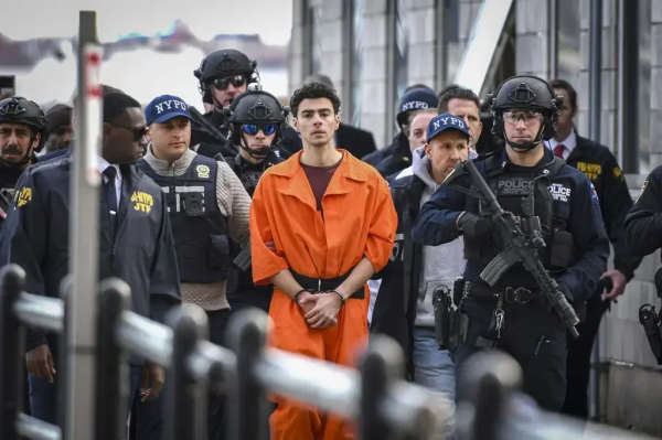 A photo of the NYPD in full combat gear moving Luigi Mangione shackled and dressed in prison orange.