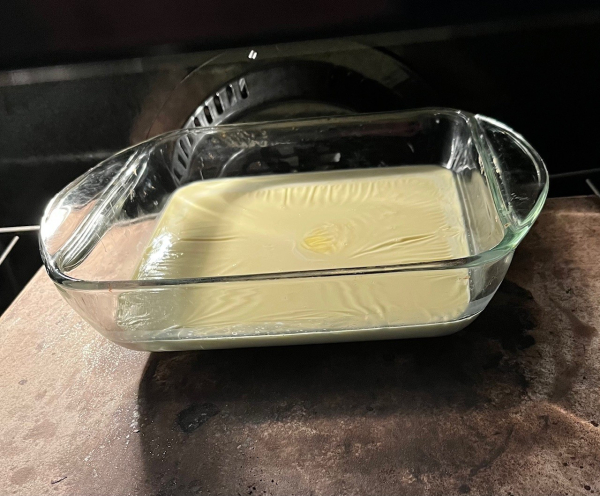 A pan of cream heats in the oven. It is a buttery golden yellow. 