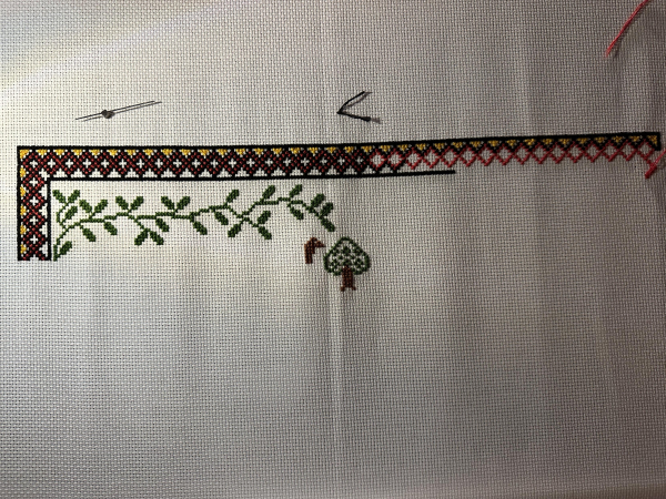 Cross stitch sampler. Foliage and a tree are visible, as is the head of a deer. 