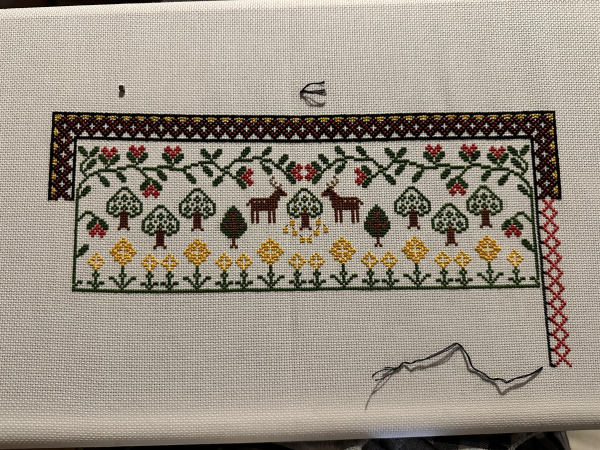 Top panel of a cross stitch sampler. The decorative border is being extended down the right hand side and it partially completed 