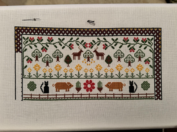 Partially completed (that’s a lie, there’s loads more to do) cross stitch sampler. The bottom section has pigs and large black cats in it. Below them is a fence I have recently finished. 