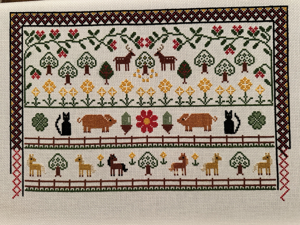 Work in progress cross stitch sampler. The bottom section shows six horses between two fences 