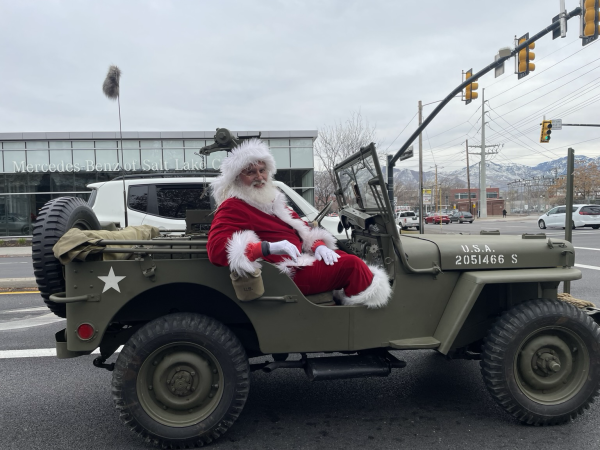 Santa in an old military jeep smiling at the camera. 