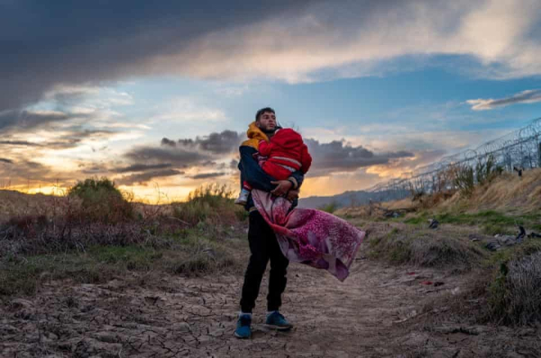 Mexican father carrying his daughter to the US Southern border