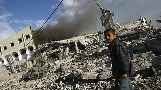 Color photograph of a child amidst ruined buildings and rubble.