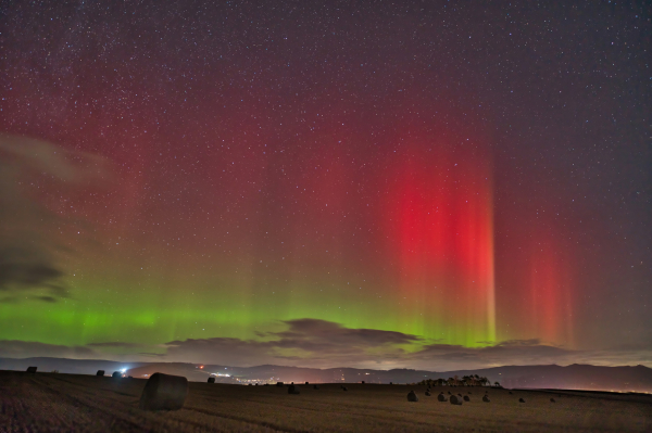 An image of the Aurora Borealis lighting up the sky with fields below. Aberdeenshire, Scotland