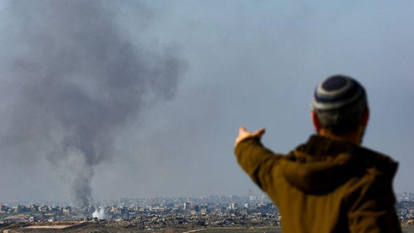 Un home observa, des del sud d'Israel, una columna de fum sobre la Franja de Gaza per un bombardeig (Reuters/Kai Pfaffenbach)