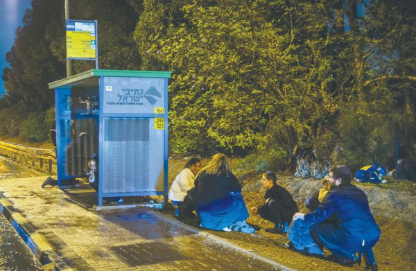 
PEOPLE TAKE cover as a siren warns of an incoming missile fired from Yemen, near Rehovot.
(photo credit: YOSSI ALONI/FLASH90)
