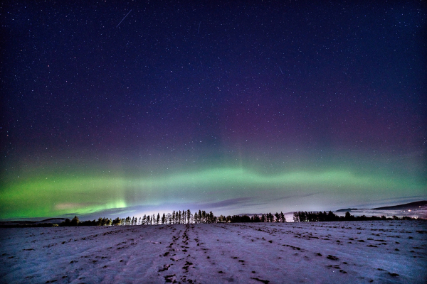 An image of a snowy landscape with an Aurora arc in the sky above. Aberdeenshire, Scotland