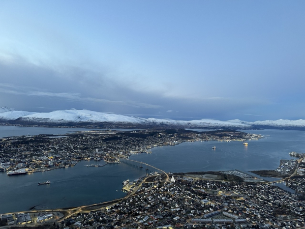 Aerial view of Trømso city with the sea approaches and snowy mountains in the far distance 