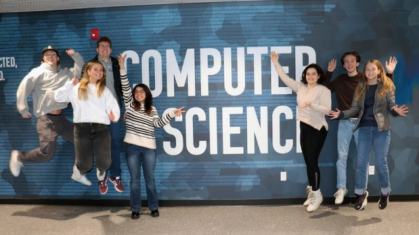 People jumping next to a mural that reads "computer science."