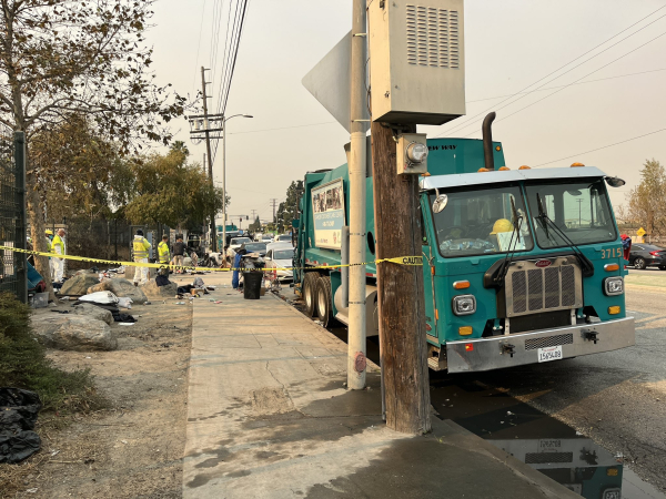 Government workers in masks to protect themselves from the LA fire smoke steal homeless people's possessions and throw them into a trash truck. They leave the homeless to fend for themselves without their basic survival supplies like tents and cooking gear.