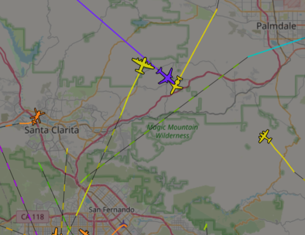 Map of area between San Fernando and Palmdale with planes and helicopter icons superimposed over it. The aircraft have lines representing their flight tracks behind them. Each track is colored to indicate the altitude of the aircraft. Of note are two tracks just above the center in yellow that are for the MD-80 and C-130 flying in opposite directions at a similar altitude of around 6000 feet. There is a purple aircraft and track flying towards the bottom right at a much higher altitude of 30000 feet, probably going to one of the other commercial airports.