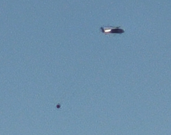 Helicopter towing a large bucket in the distance