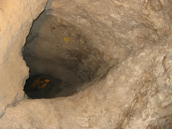 The image depicts a view of a cave or a deep shaft within a rocky environment. The walls appear to be made of stone or earth, and there is a darker area visible at the bottom, which may indicate depth or a hidden area inside the cave. The overall texture looks rugged and natural, typical of cave formations.

Image Credits: Wikimedia / Deror avi / CC BY-SA 3.0