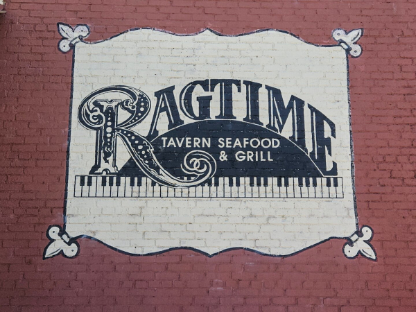 Ragtime restaurant signage. Fancy lettering in black in white mixed over piano keys, and "Tavern, Seafood, and Grill"