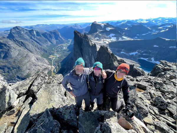 3 hikers on the summit with a deep view into the valley below